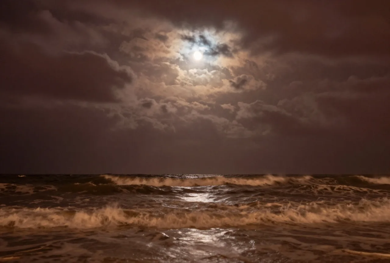 Ein stürmisches Meer bei Nacht unter schweren Wolken mit hohen dunklen Wellen und durchbrechendem Mondlicht